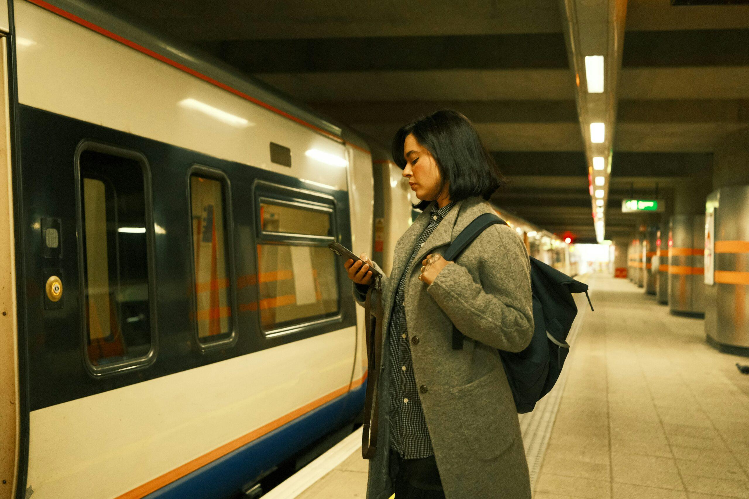 A woman stands confidently in front of a train, with the train's sleek design visible in the background.