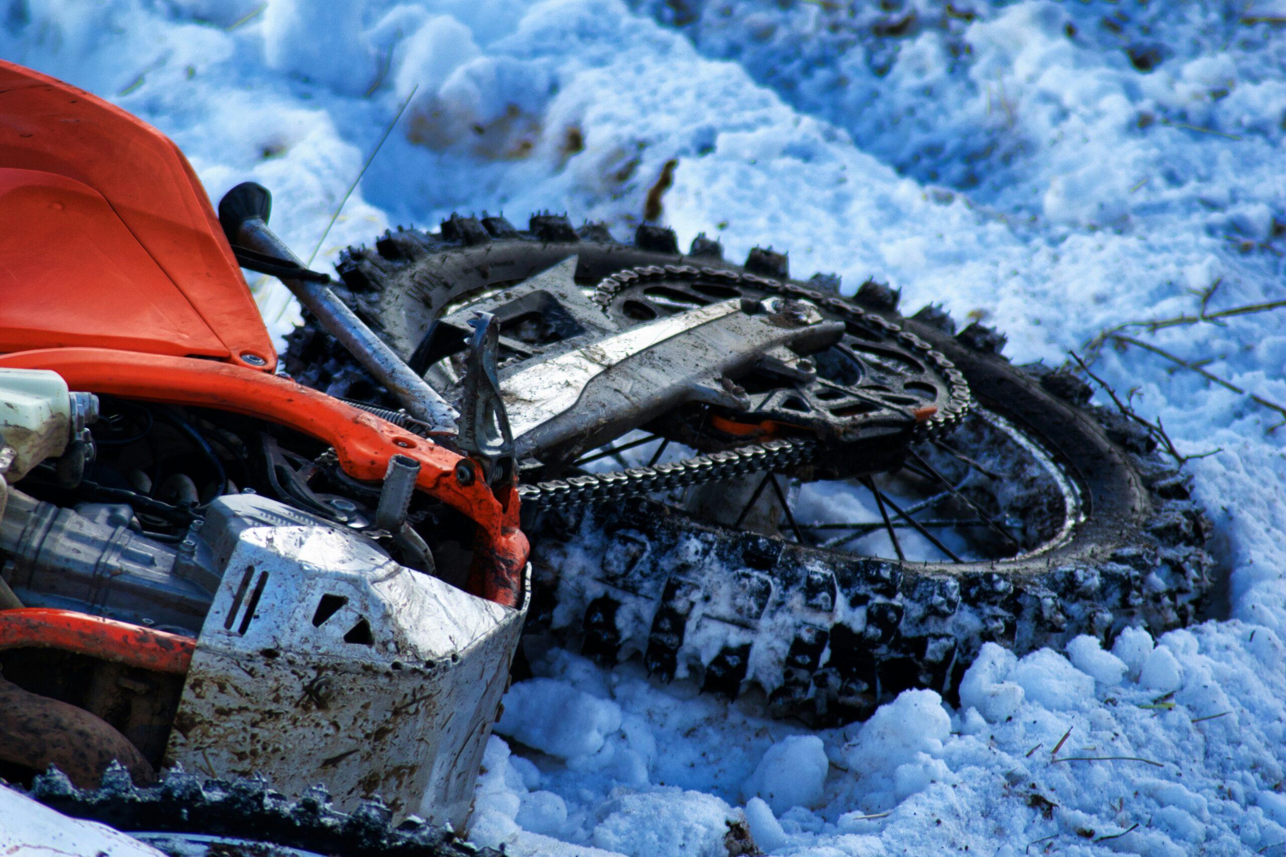 A motorcycle parked in a snowy landscape, with snow covering its seat and handlebars.