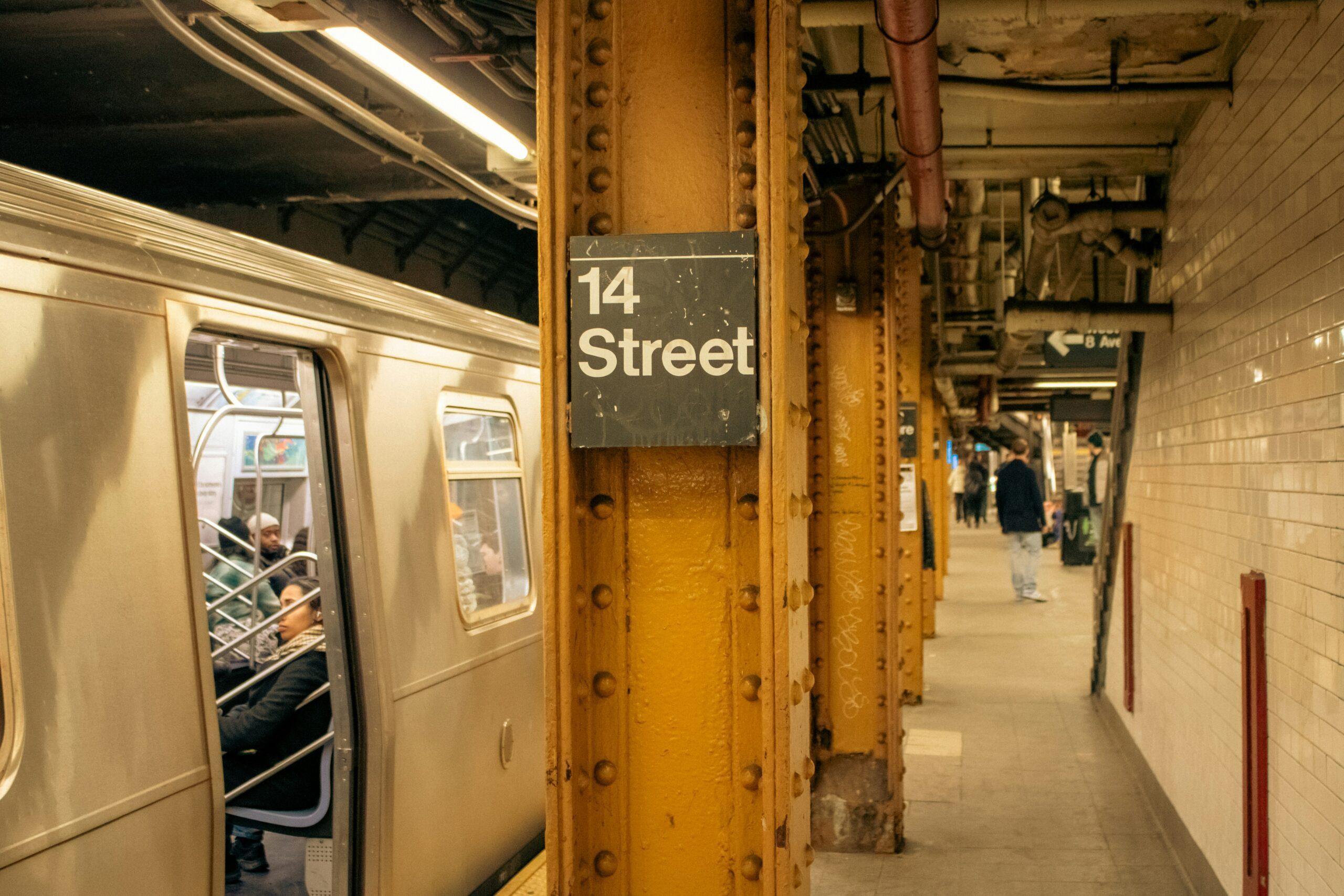 A subway train is parked at a station, with empty platforms and signage visible in the background.