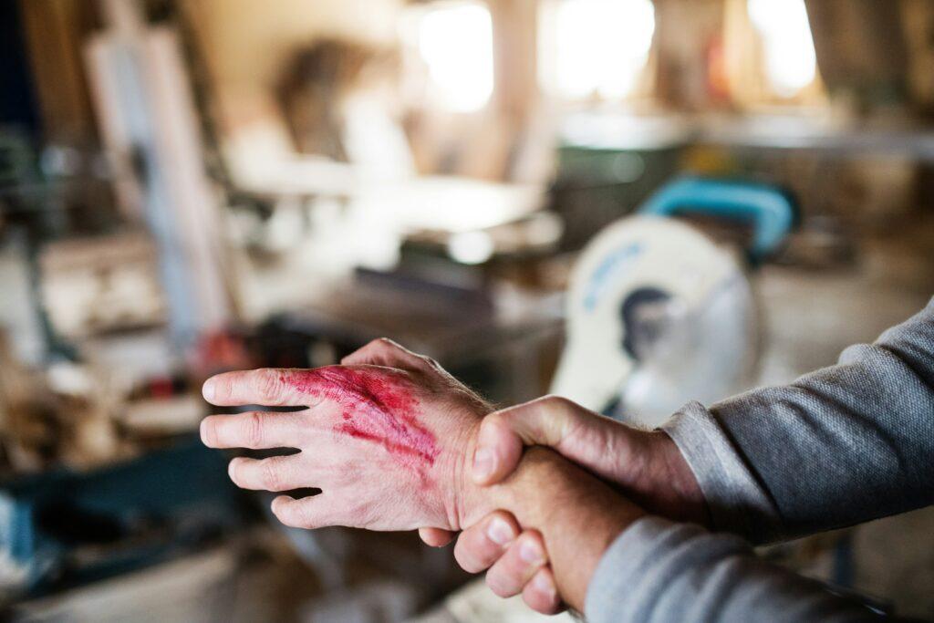 A man with a bloody hand gripping a piece of wood, suggesting a recent injury or violent encounter.