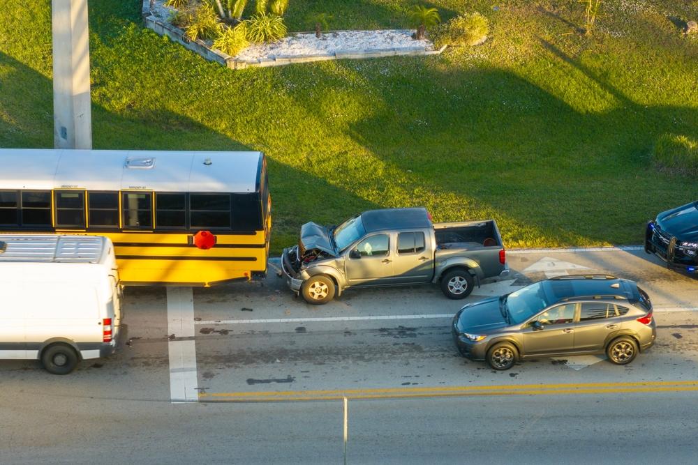 Traffic accident on American street. First responders helping victims of school bus and car crash on road in USA. Aerial view of emergency services responding to accident site