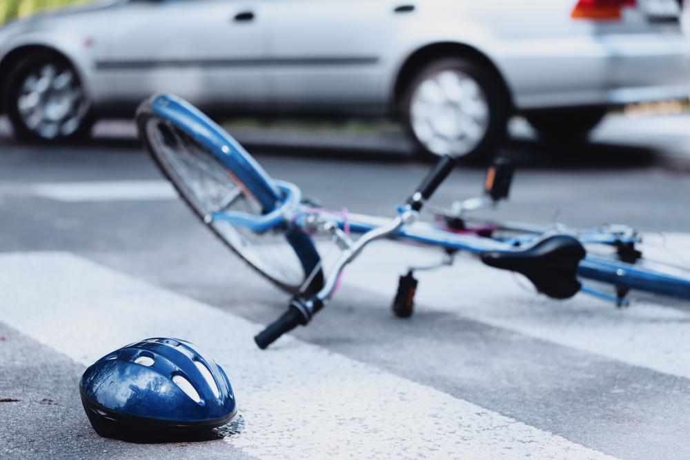 Bicycle and a helmet lying on a crosswalk near a car after an accident