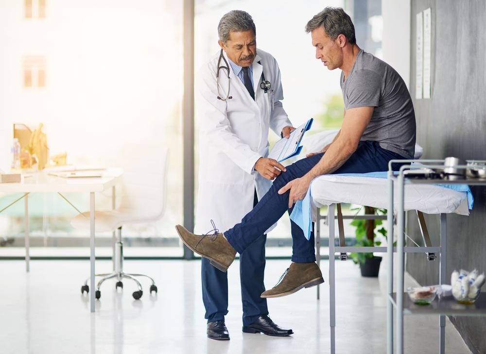 Doctor examining a patient's knee in a clinic exam room