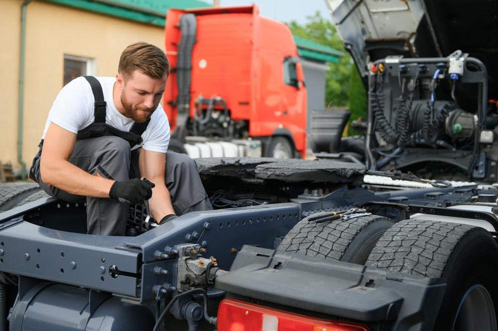 Mechanic working on the exposed chassis of a semi-truck