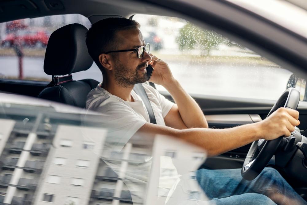 Man driving while holding a phone to his ear