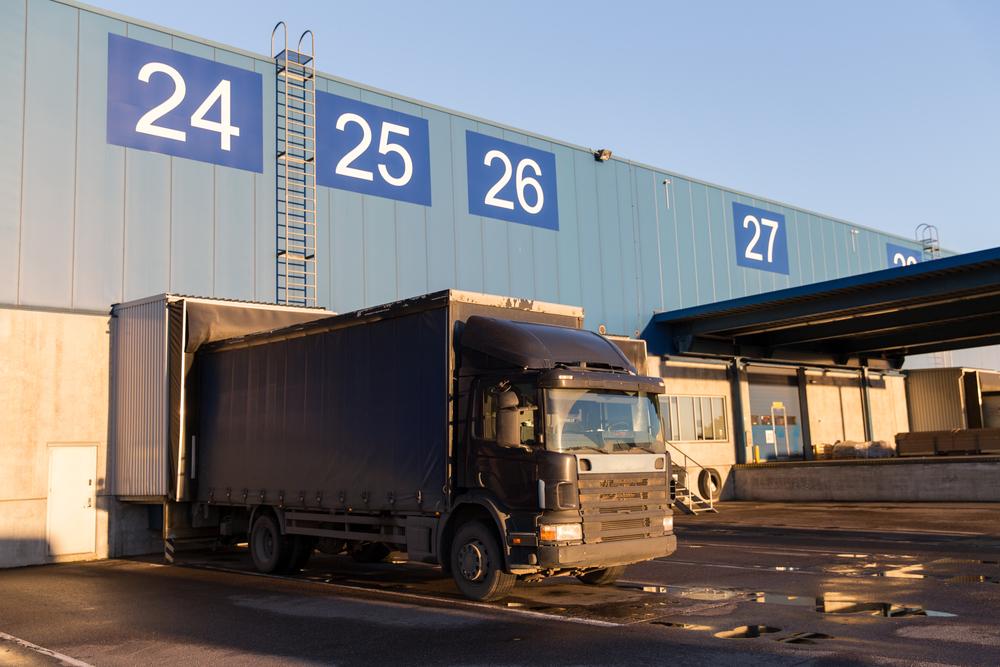 Truck parked at a warehouse loading dock, with numbered bays: 24 25 26 27