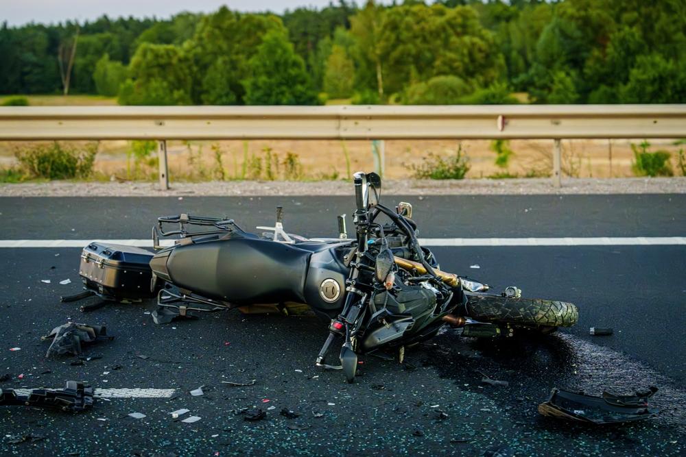 Wrecked black motorcycle lying on a highway with scattered debris after a crash